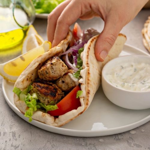 Chicken souvlaki with fresh vegetables on a flatbread with tzatziki sauce